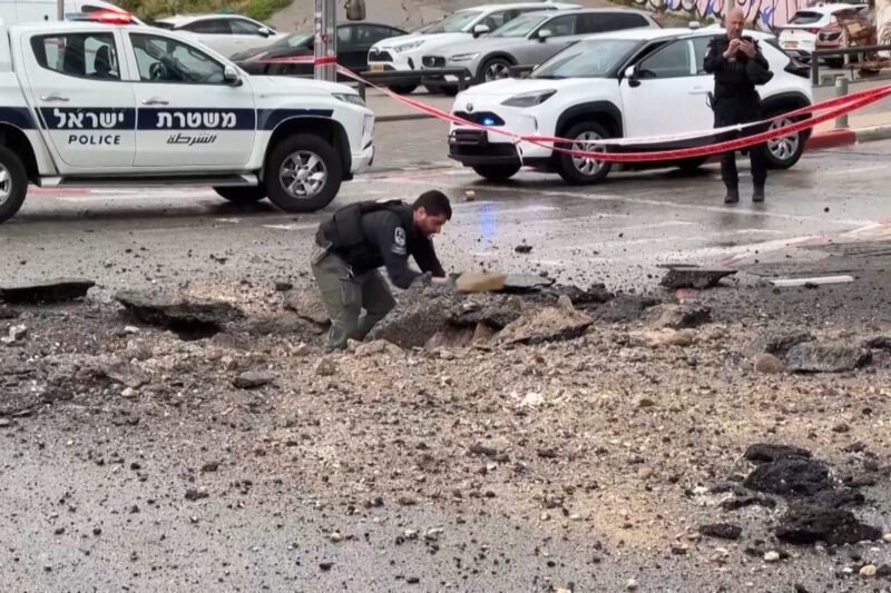 Israeli police inspect damage on the road after missile impact | US-Israel war on Iran